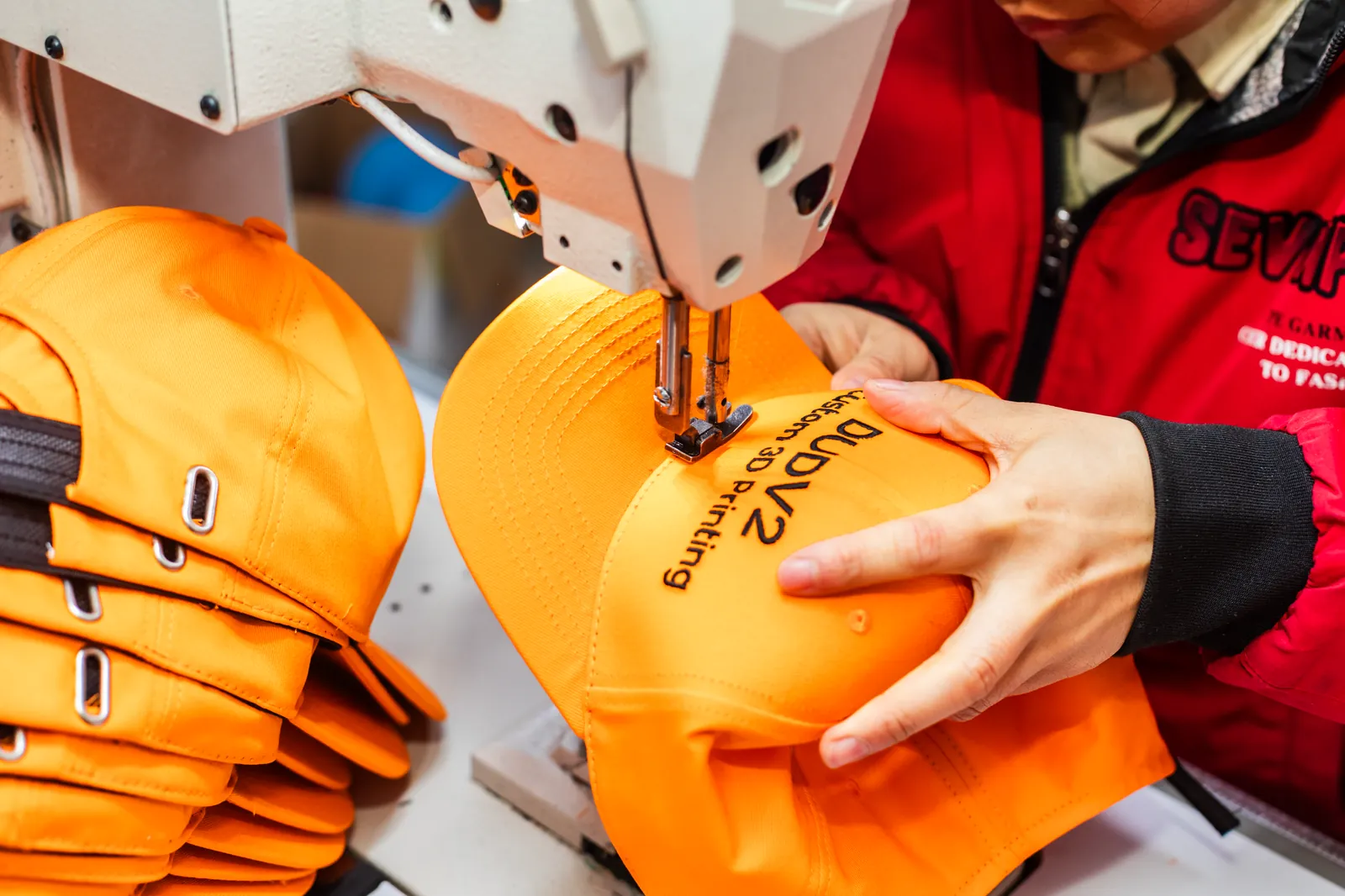 Operator embroidering yellow caps